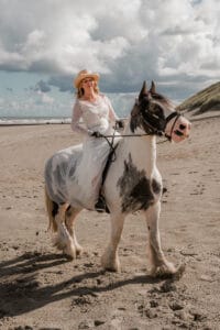 Eine Braut reitet auf einem Pferd am Strand von Norderney zu ihrer Trauung-