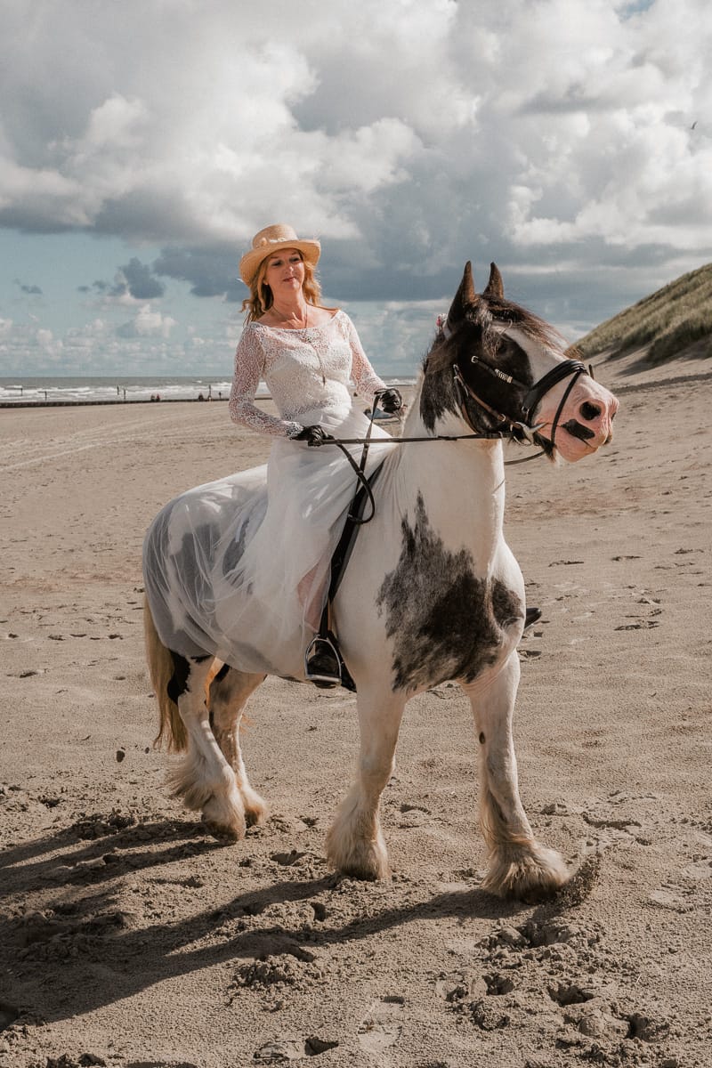 Eine Braut reitet auf einem Pferd am Strand von Norderney zu ihrer Trauung-