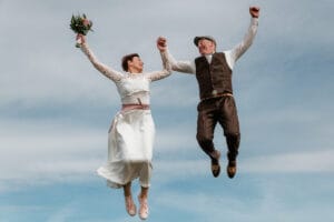 Fliegendes Hochzeitspaar vor dem Himmel auf Norderney nach ihrer Trauung im Badekarren.