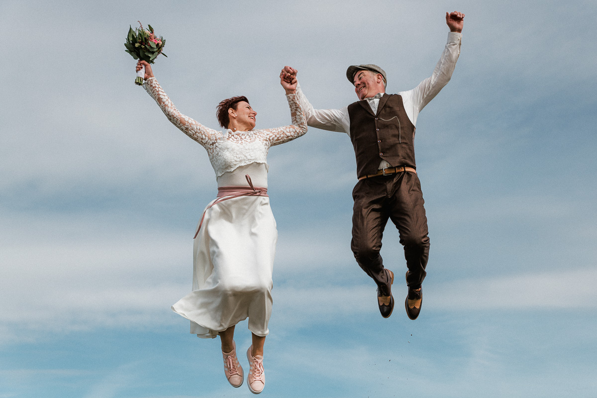 Fliegendes Hochzeitspaar vor dem Himmel auf Norderney nach ihrer Trauung im Badekarren.