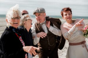 Eine Hochzeitsgesellschaft bei ihrem kleinen Trauung am Badekarren am leeren Strand.