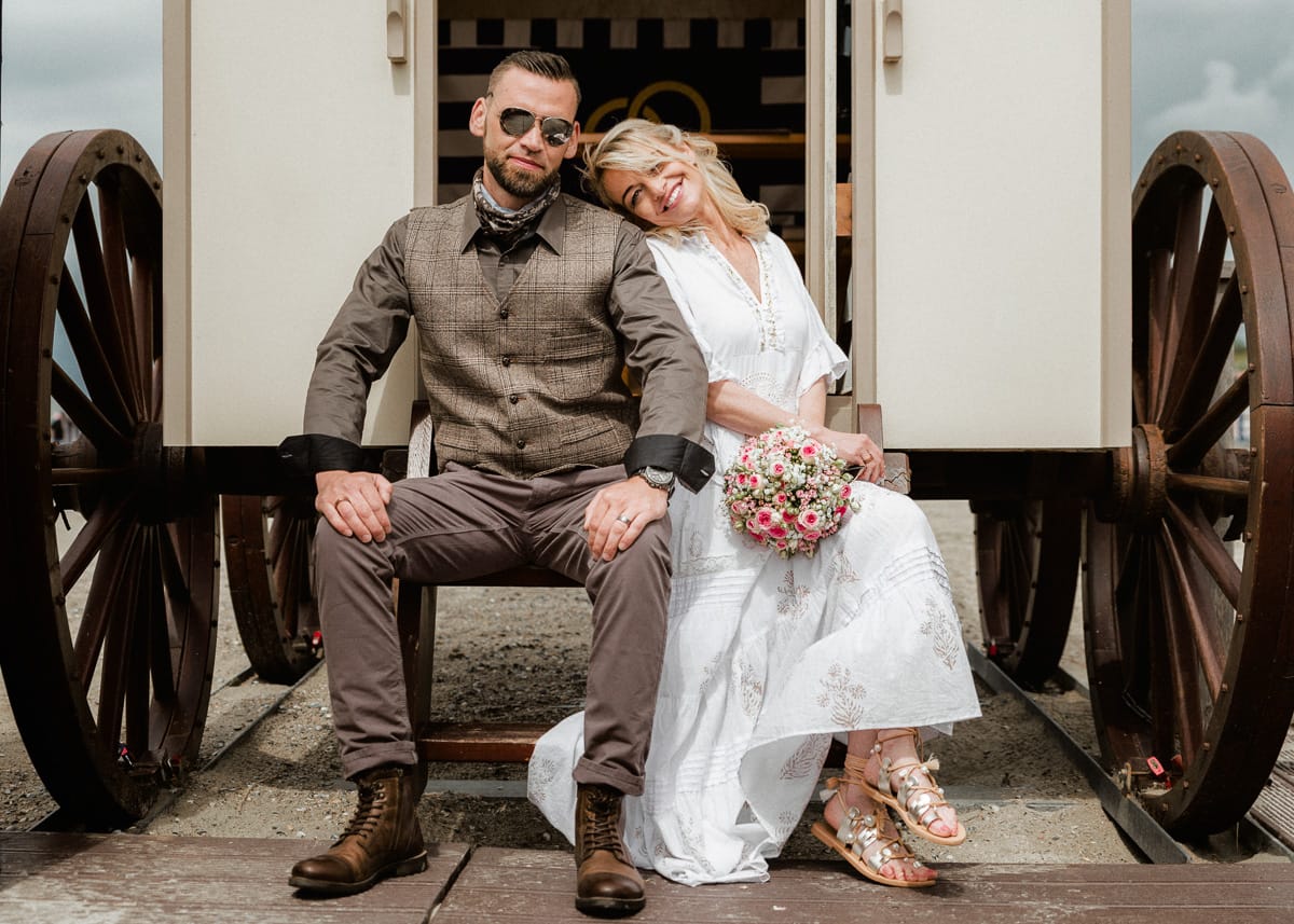 Das Hochzeitspaar freut sich ueber die letzten Sonnenstrahlen und sitzt vor dem Standesamt auf Norderney am Strand.