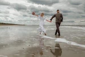 Bei epischem Himmel spaziert ein Brautpaar am Flutsaum am Weststrand der Insel Norderney.