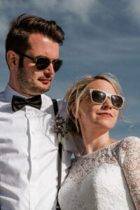 Brautpaar mit Sonnenbrille im K64 Look vor blauem Inselhimmel auf Norderney nach ihrer Trauung im Badekarren.