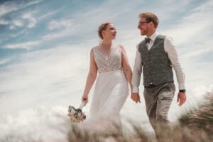 Hochzeitspaar Hand in Hand im Strandhafer mit Fotograf Markus Hirsch auf der Insel Norderney.