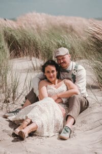 Paar sitzt auf der Insel Norderney in den Duenen am Hochzeitstag.