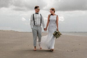 Modisches Brautpaar beim Shooting am Strand bei weichem Licht.