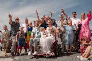 Paar mit ihrer Hochzeitsgesellschaft bei Gruppenaufnahme auf Norderney in lockerer Stimmung.