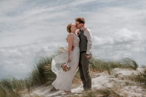 Frisch getrautes Paar kuesst ich im Strandhafer auf Norderney.