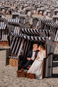 Brautpaar kuesst sich in einem Meer aus Strandkoerben auf Norderney am Nordstrand von Markus R. Hirsch.